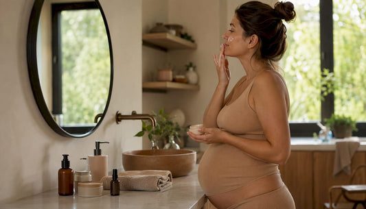 Pregnant woman applying skincare by mirror